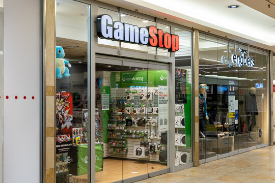 DRESDEN, GERMANY - 29. January 2021: GameStop store front in a shopping center. Big illuminated logo shining during Covid-19 lockdown while the retail shop remains closed.