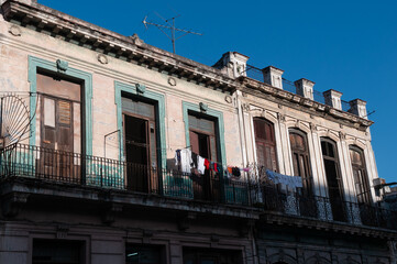 Fototapeta na wymiar Clothes hanging on a balcony of a deteriorated classic-style facade on a street in Havana. Havana. Cuba