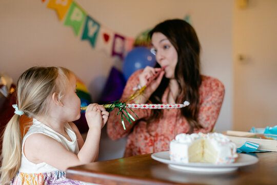 Young Girl and Mom Using Noisemakers at Party