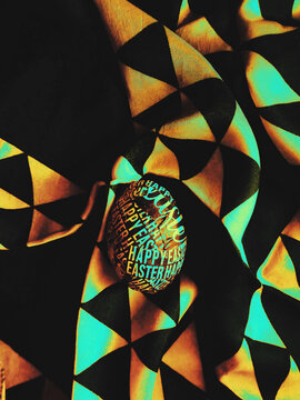 Custom, colorful and vibrant DIY Easter eggs surrounded with the dark, contrasty rainbow dotted fabric background with copyspace
