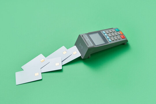 Terminal and blank credit cards on green background.