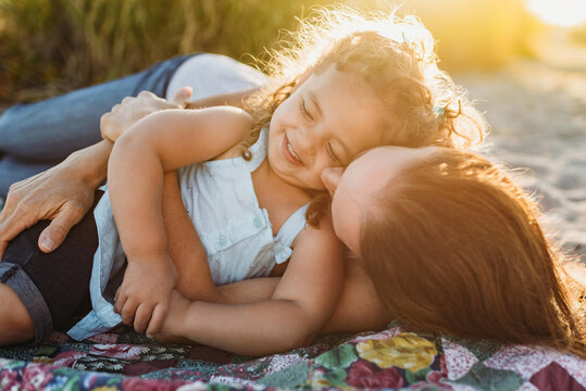 Mom and young daughter outdoors on quilt