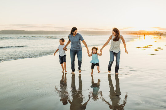 Modern family running on beach at sunset