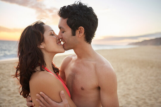 Couple kissing on the beach on vacation at sunset