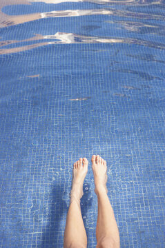Woman on vacation with feet in pool water