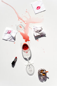 Broken wineglass with ashtray and lipstick