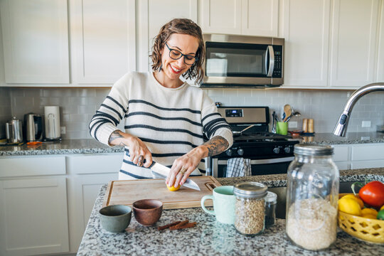 Happy woman slicing lemon in home kitchen