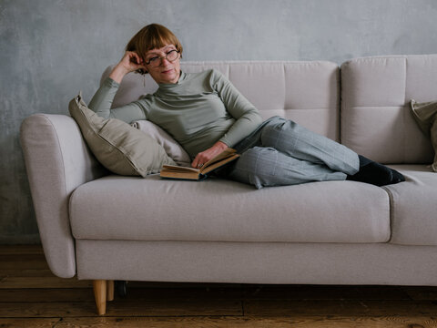 Senior woman reading book on the couch