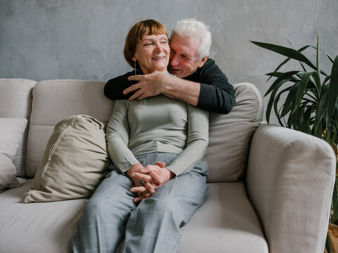 Senior man hugging wife at the neck laughing 