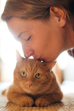 young woman kissing ginger cat