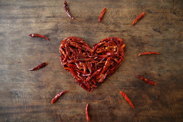 Dried chilli heart shape with chilli 'sparks' on a rustic wooden table
