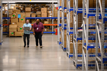 Two workers with laptop computer at warehouse