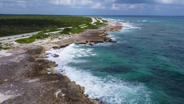 Aerial drone view of turquoise ocean water waves crashing onto beach of tropical island Cozumel in Mexico