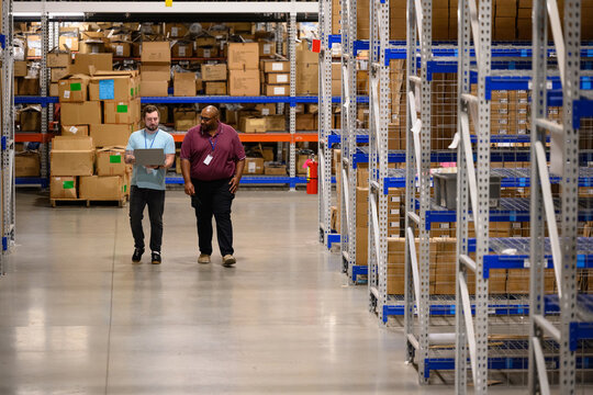 Two workers with laptop computer at warehouse