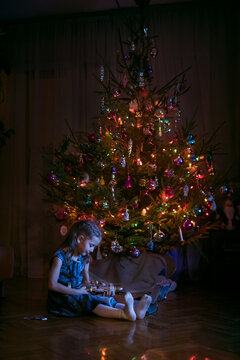 Little girl playing with nutcracker by a Christmas tree