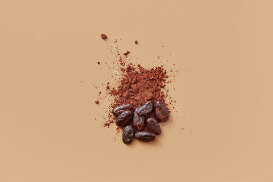 Cocoa powder and beans on beige background