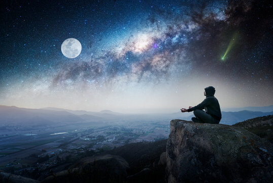 person sitting on the top of the mountain outdoors  meditating or contemplating the starry night with Milky Way background