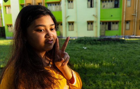 A girl showing V sign at outdoors in evening time