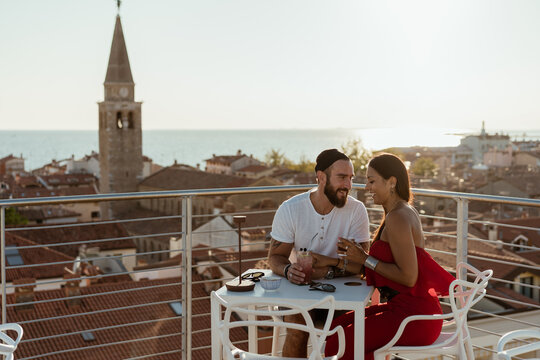 Couple drinking a cocktail at the rooftop bar sunset