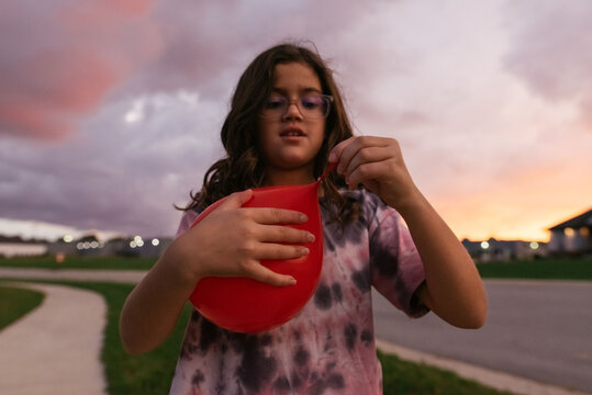 Tying a knot in a red balloon. 