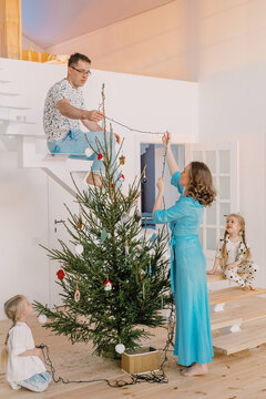 Family of four decorating a Christmas tree 