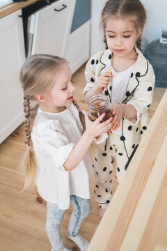 Two Kids Eating Gummy Worms Out Of A Glass Jar