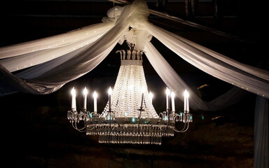 A lit up chandelier hanging with white cloth