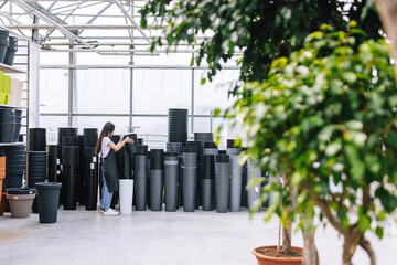 Female gardener laying colorful flowerpots in storage