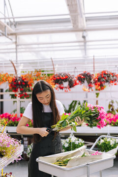Woman pruning piece of flowers in store 