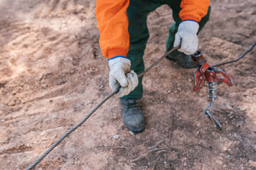 Woodcutter pulling steel rope in forest