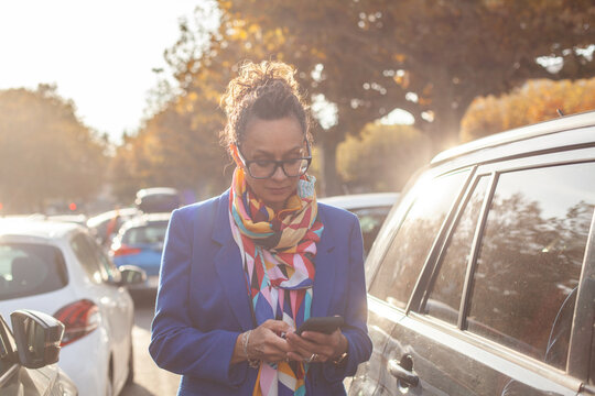 mature business woman using smartphone near her  car