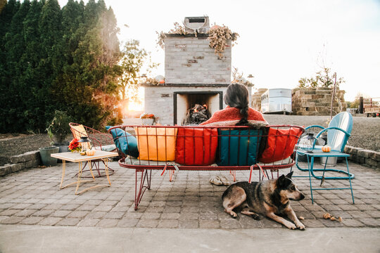 owner and dog sitting on patio by outdoor fireplace