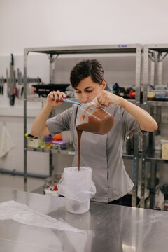 Woman pouring chocolate cream in pastry bag