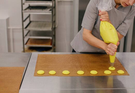 Anonymous baker with yellow dough in pastry bag 