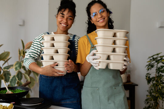 Happy cooks holding packed lunches