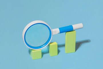 A magnifying glass lying on columns of different height