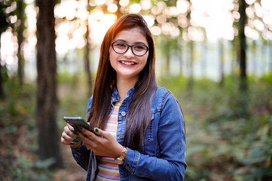 Beautiful young girl surfing smartphone in forest