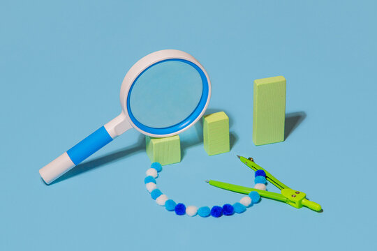 A magnifying glass lying on columns to compasses