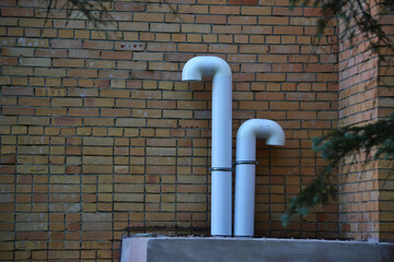 White air duct piping on a red brick wall