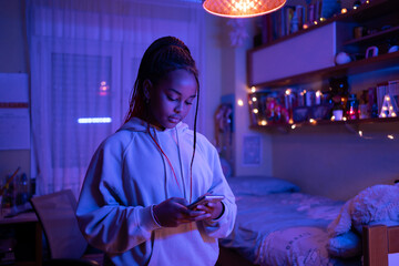 Teen Black Girl Texting With Her Phone In The Bedroom. 