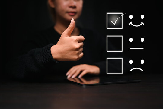Young woman showing thumb up with smiley face icon to evaluate product and service.