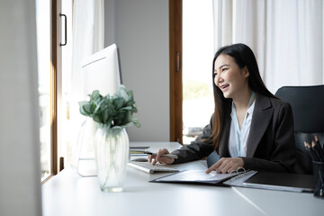 Smiling businesswoman working with computer in bright modern workplace.