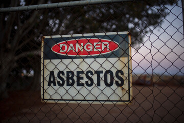 Danger abestos sign behind a metal fence during sunset in Adelaide, South Australia