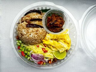Thai traditional food Khao Khlook Kapi; shrimp paste rice with caramelized pork condiment, dried shrimp, green mango, chilies, lime, shallot , fried egg and chopped long beans