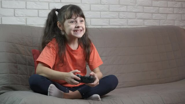 Child play video game on playstation. A view of happy little girl play video game on her playstation in the room.