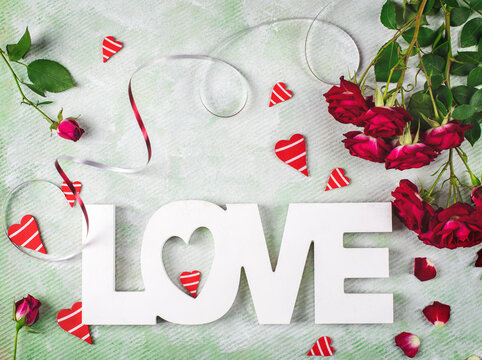 Festive composition of love for Valentines day made with red roses, hearts and word Love. Flat lay.