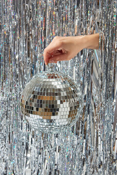 Female hand holding mirrored disco ball