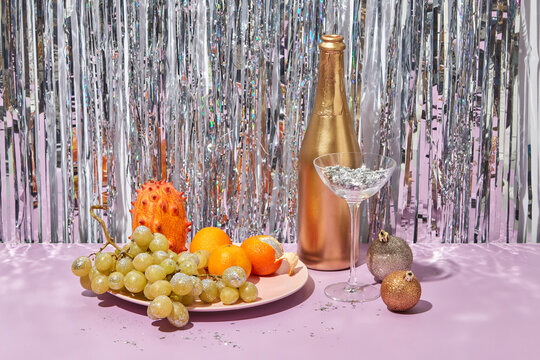 Champagne bottle, glass and fruits on festive table