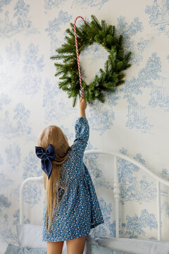 Kid Decorating Fir Wreath On Wall