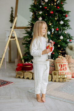 A girl with a nutcracker toy near Christmas tree